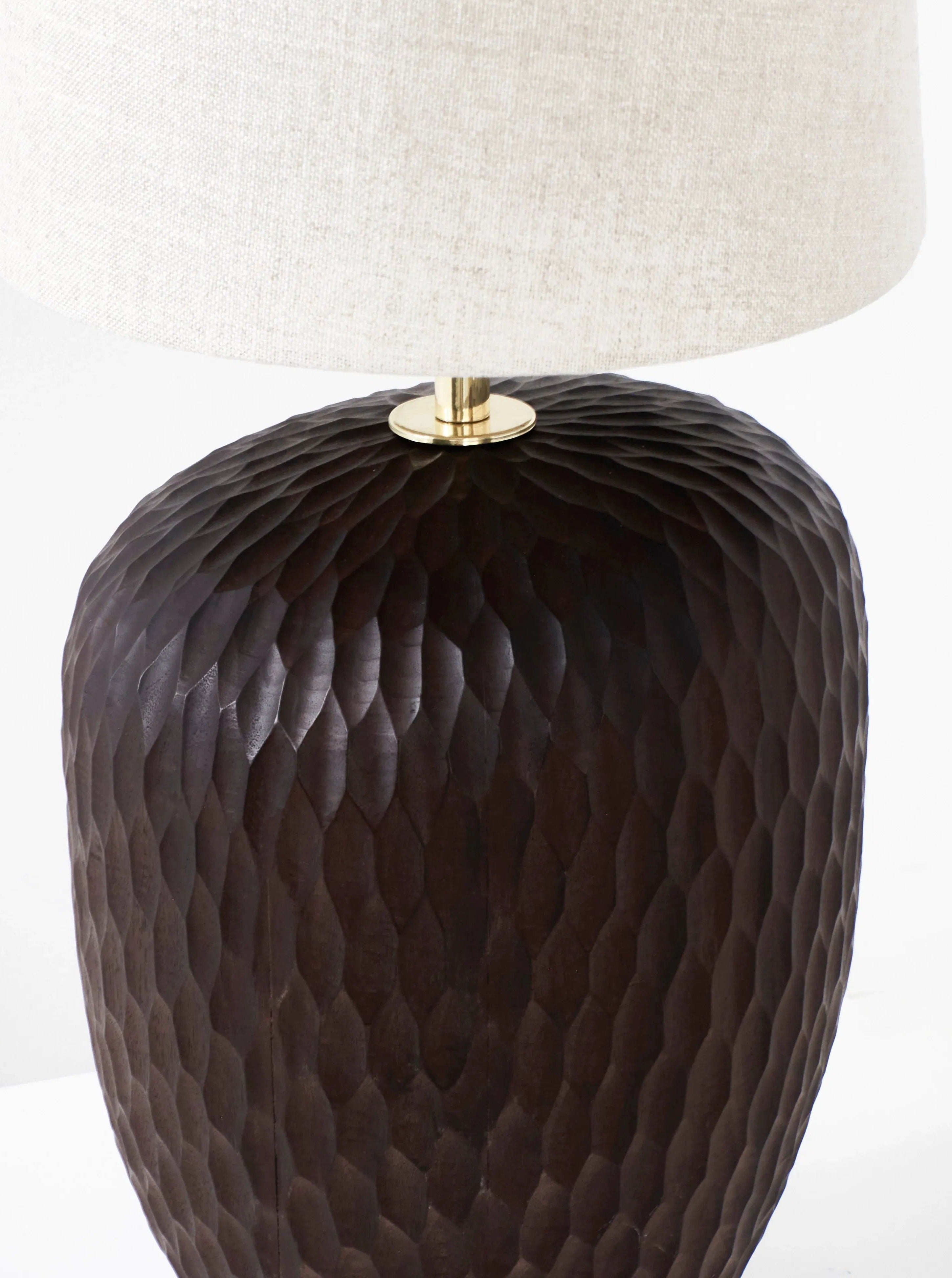 A Large Foz Lamp with a textured, dark brown base that resembles a hammered surface from Project 213A. The lamp features a white, fabric lampshade and a brass neck connecting the shade and base. This artisanal light exudes modern elegance with its handmade craftsmanship.