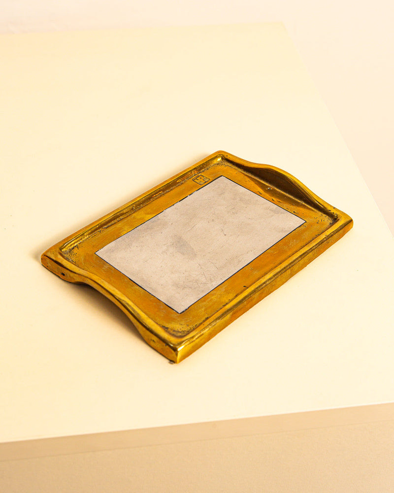 The Vide-poches by David Marshall 80’s for Treaptyque is a rectangular brass-and-silver tray with a gold frame, silver center, and slightly raised curved edges, showing '80s design influence and signs of wear. It rests on a light surface.