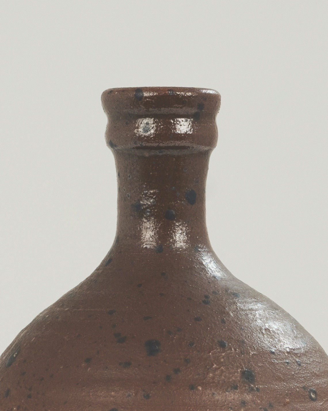 Brown stoneware vase neck detail showing glazed finish and speckled texture