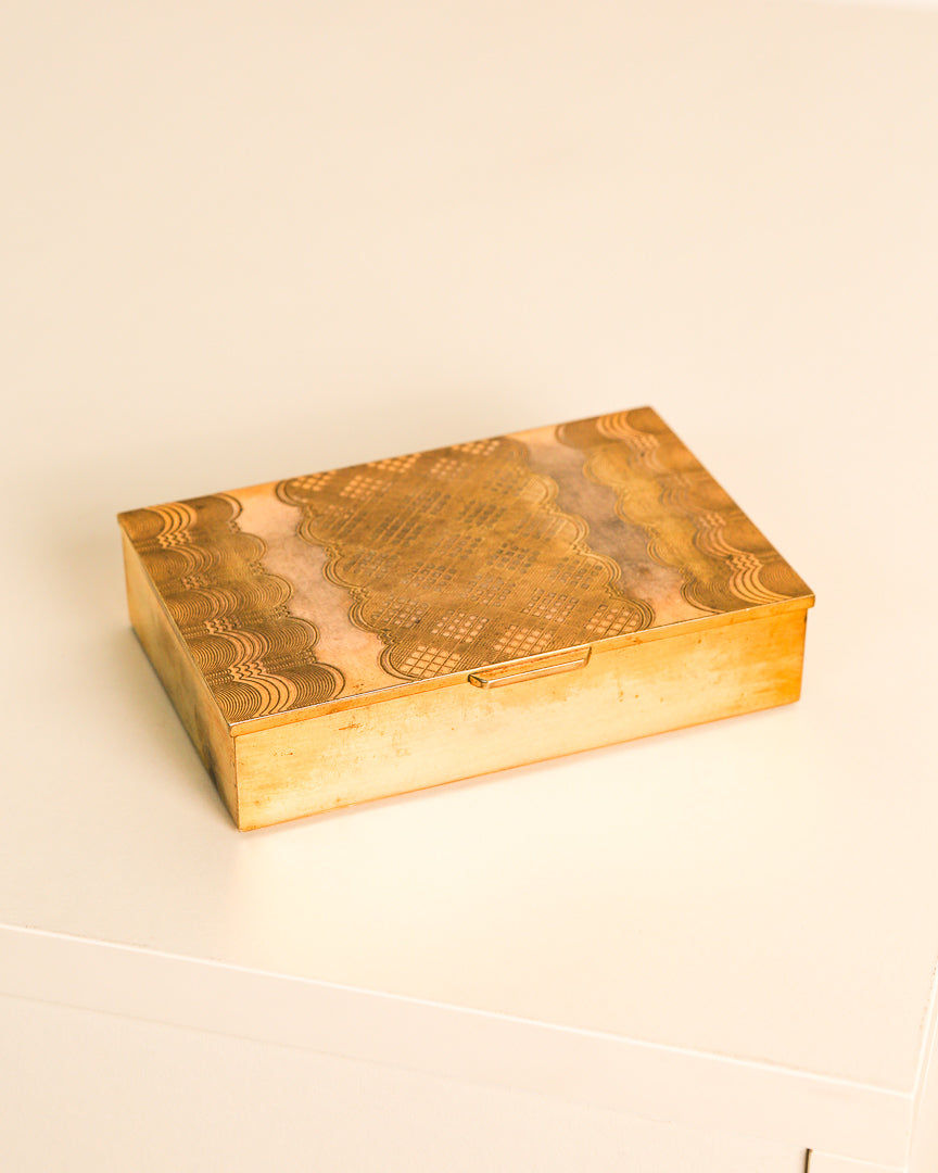 Engraved brass storage box with ornate cloud patterns and cross-hatch design