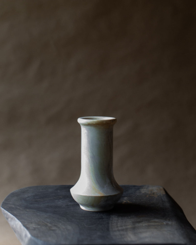 Vintage ceramic vase in pale green glaze on dark stone surface