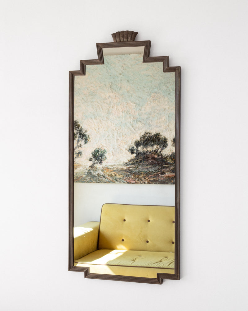 Art Deco bronze mirror reflecting yellow armchair in interior setting