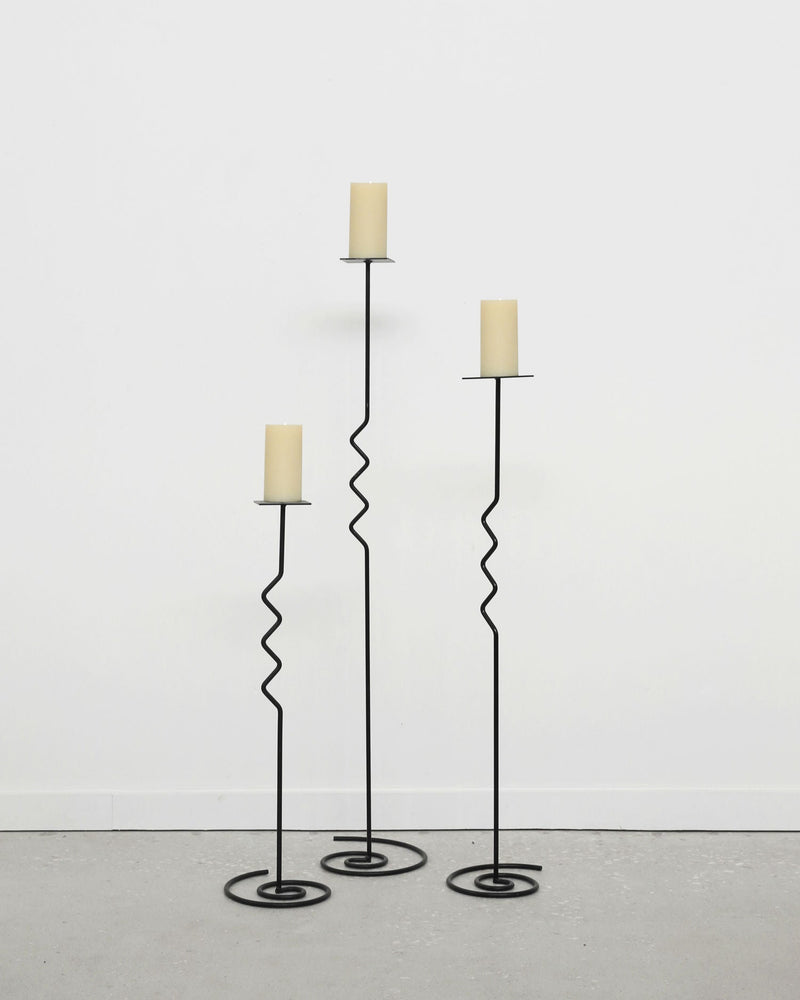 Set of three black metal spiral floor candleholders with cream candles