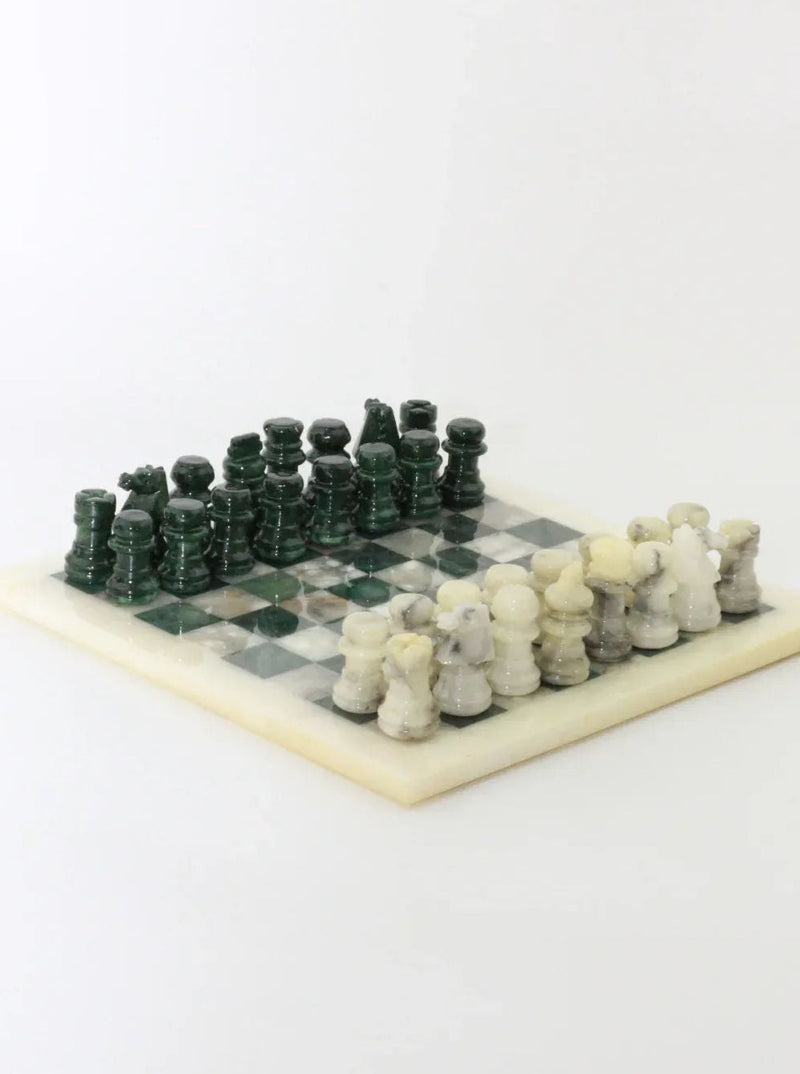 A Vintage Green and White Marble Chessboard by Boga Avante Shop displayed on a white surface. The vintage chessboard features alternating green and white squares, with elegant green and white marble pieces arranged for a game. The pawns, bishops, knights, rooks, queens, and kings are all distinguishable and neatly set up.