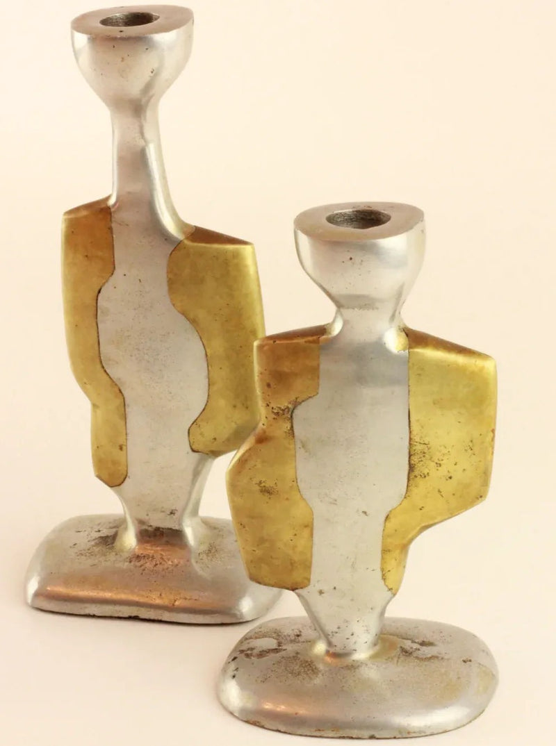 Two vintage Brutalist Candleholders with abstract, human-like shapes stand upright. Each holder, crafted by Boga Avante Shop, features a combination of smooth aluminum and brass sections, creating a dual-toned appearance. The design is modern and minimalist, with a flat base and a holder at the top for candles.