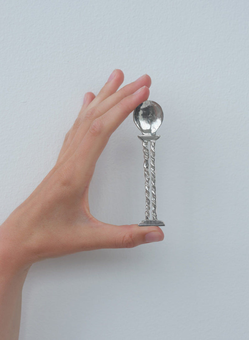 Hand holding silver twisted stem spoon showing scale and craftsmanship