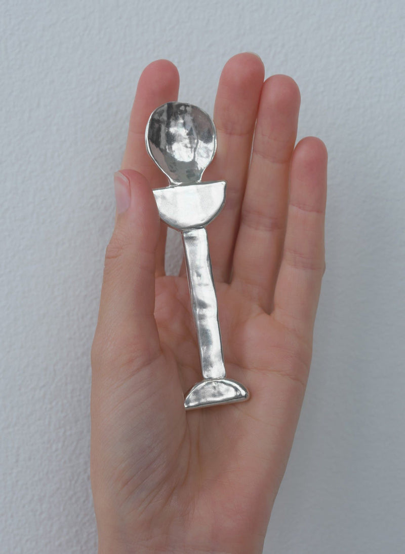Hand holding silver Lee spoon showing hammered finish detail