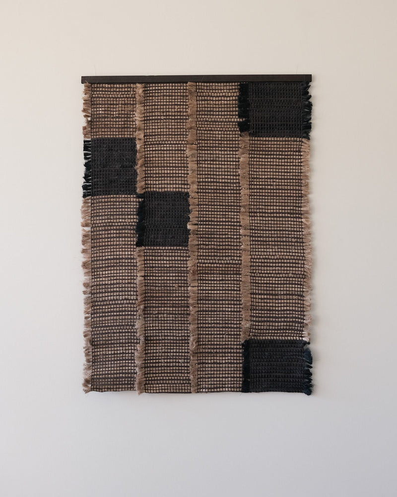 Woven textile wall sculpture with geometric black and beige pattern