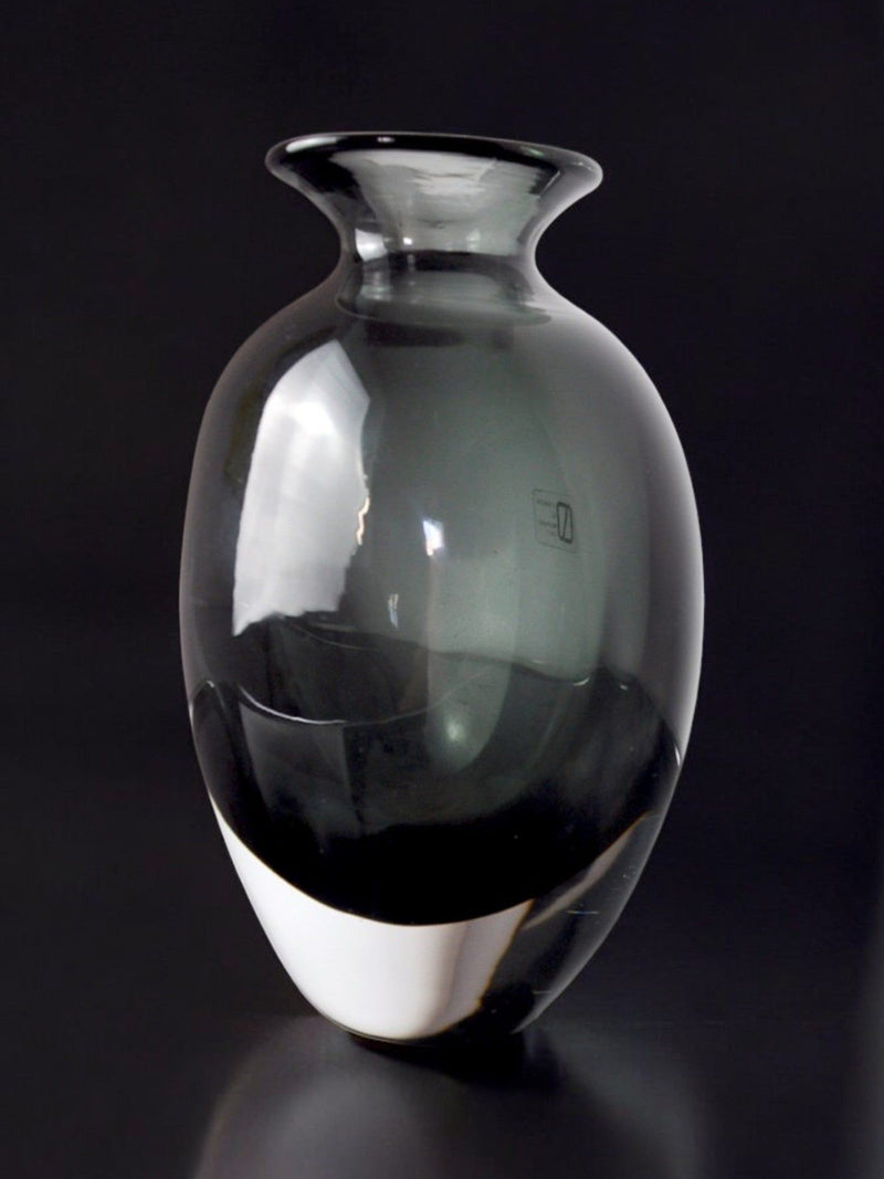 The Black vase by Vincenzo and Carlo Nason, crafted in Murano glass for Malamar Studio (Italy, 1960), features a smoky-gray transparent body with a rounded form and flared rim, highlighted by subtle reflections against a black background.