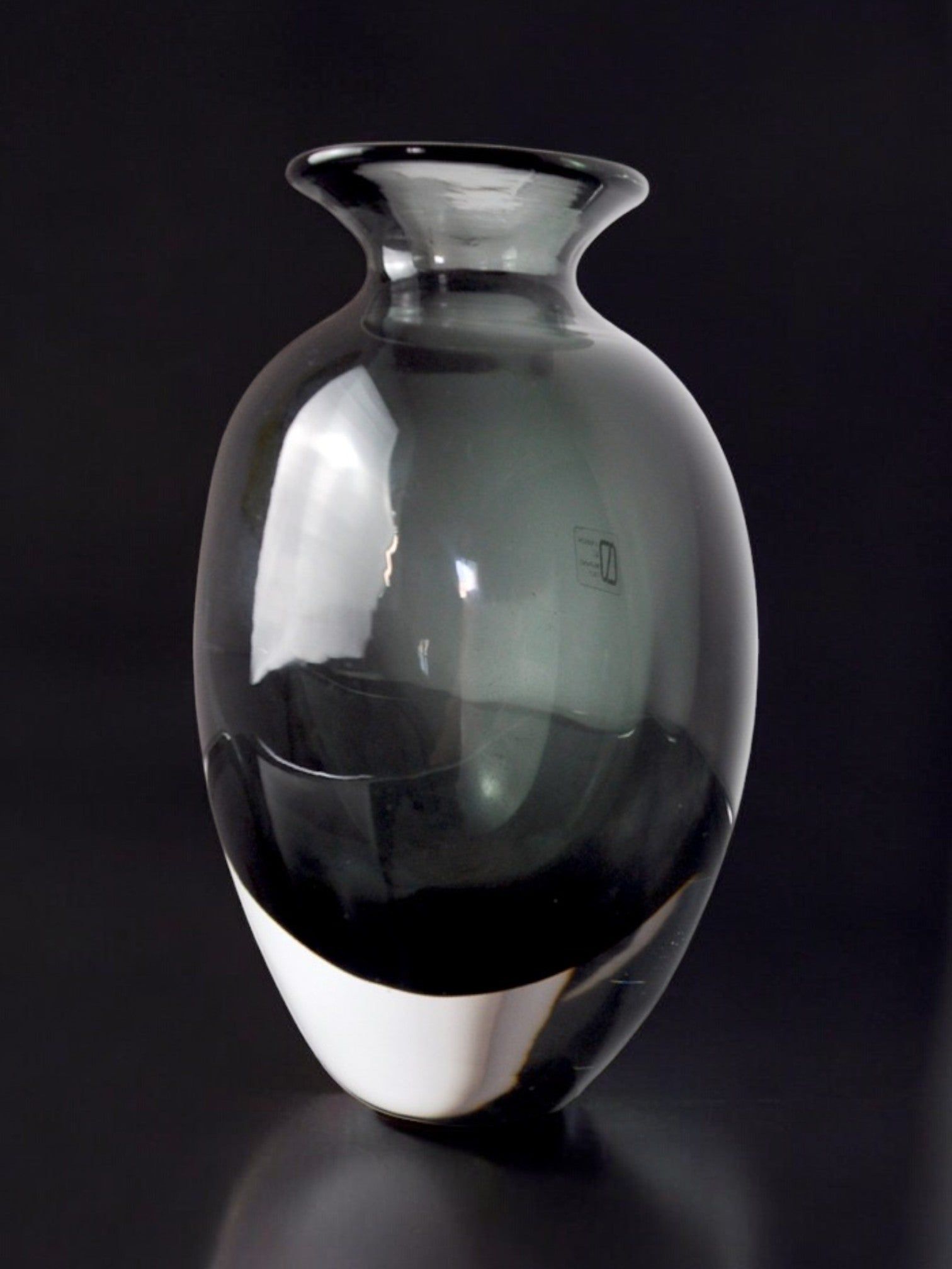 The Black vase by Vincenzo and Carlo Nason, crafted in Murano glass for Malamar Studio (Italy, 1960), features a smoky-gray transparent body with a rounded form and flared rim, highlighted by subtle reflections against a black background.