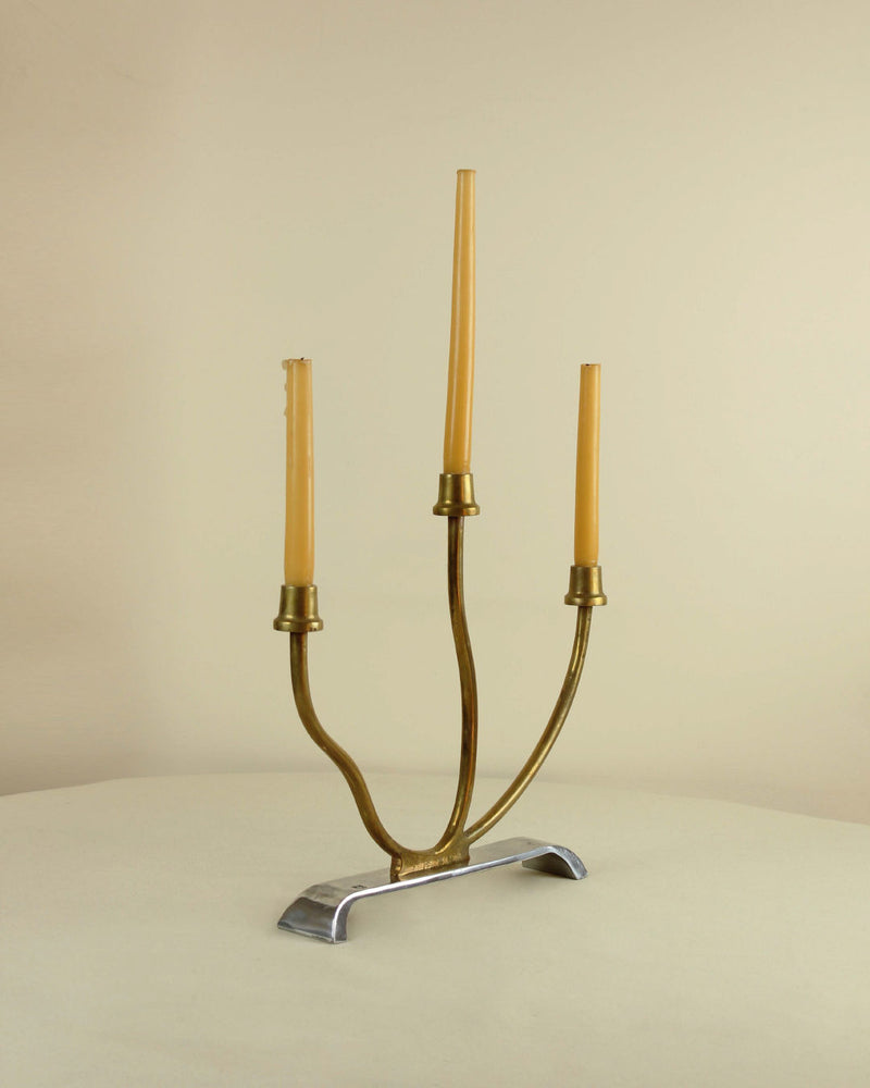 Modern aluminum candelabra with brass arms holding three candles