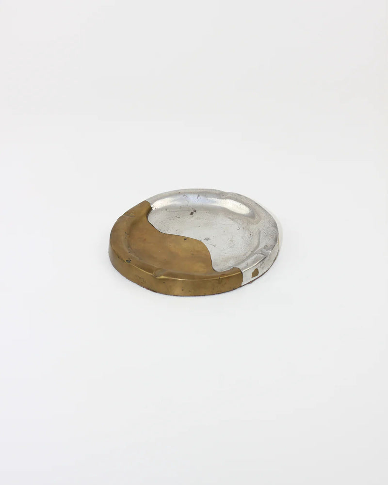 The Boga Avante Shop presents the Brutalist Ashtray, designed in aluminum and brass with a simple two-tone look. Set against a plain white background, this modern piece beautifully showcases its unique material blend.
