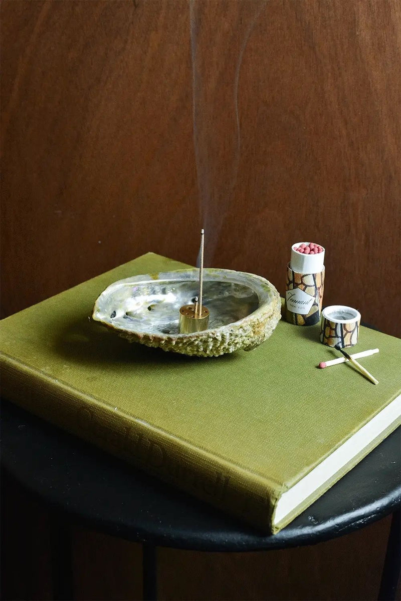 Abalone shell incense holder with brass stick and matches on green mat