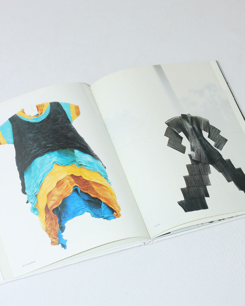 Open Issey Miyake book showing colorful garment and geometric designs