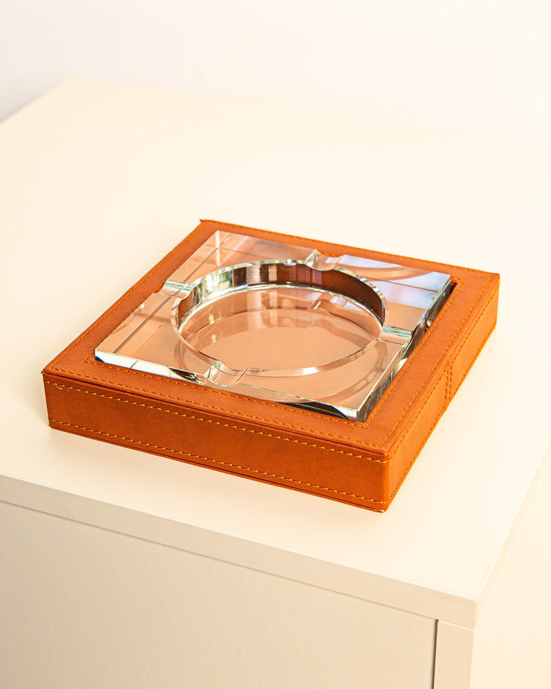 The Treaptyque Square Glass and Leather Ashtray 90s features a shiny metallic center and orange-brown stitched leather sides, bringing classic sophistication to any setting.