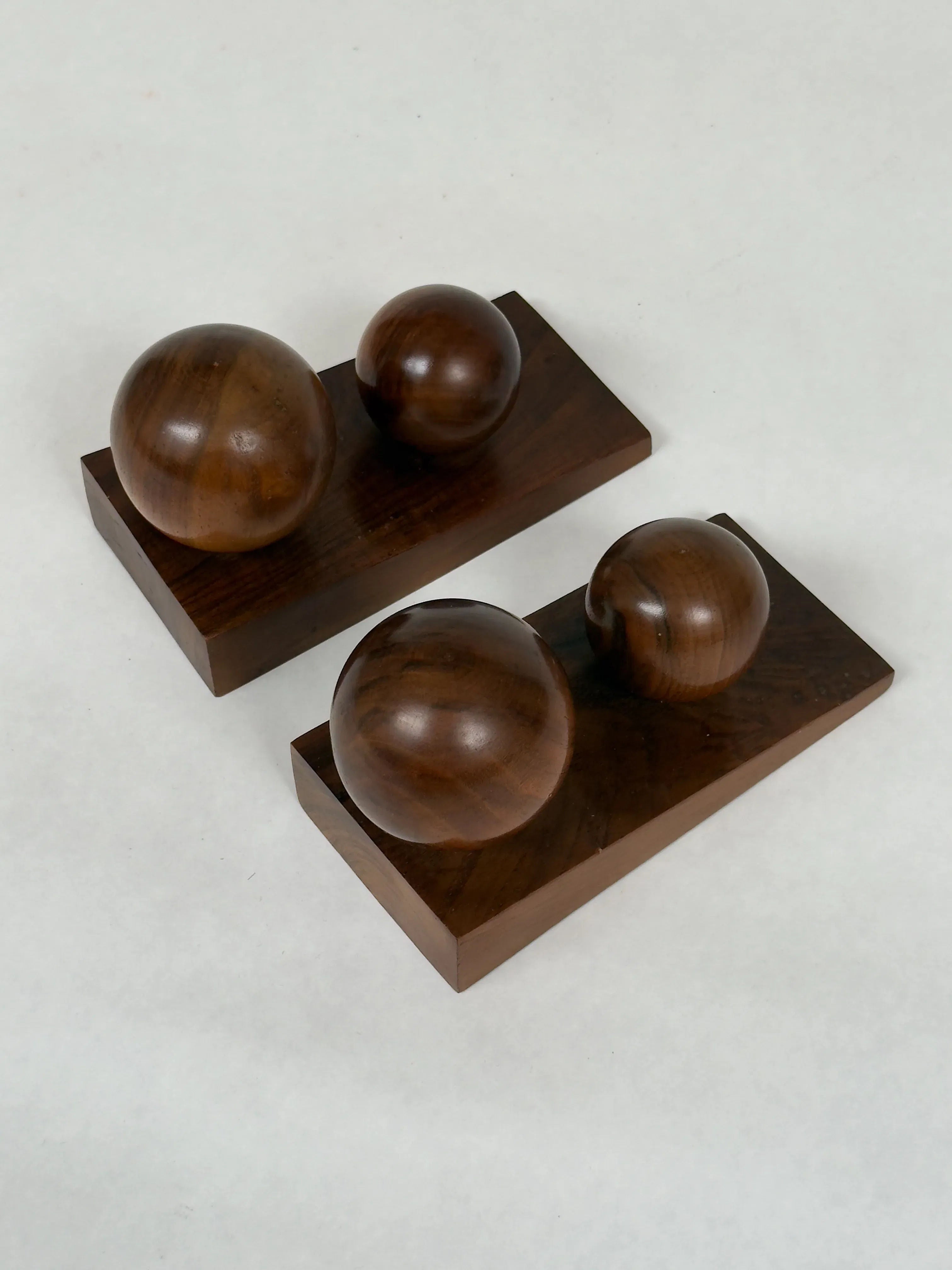 The Art Deco Bookends in Walnut by Galerie Storm feature two solid walnut spheres on a rectangular base, with one larger and one smaller sphere showcasing geometric design and visible grain patterns against a light background.