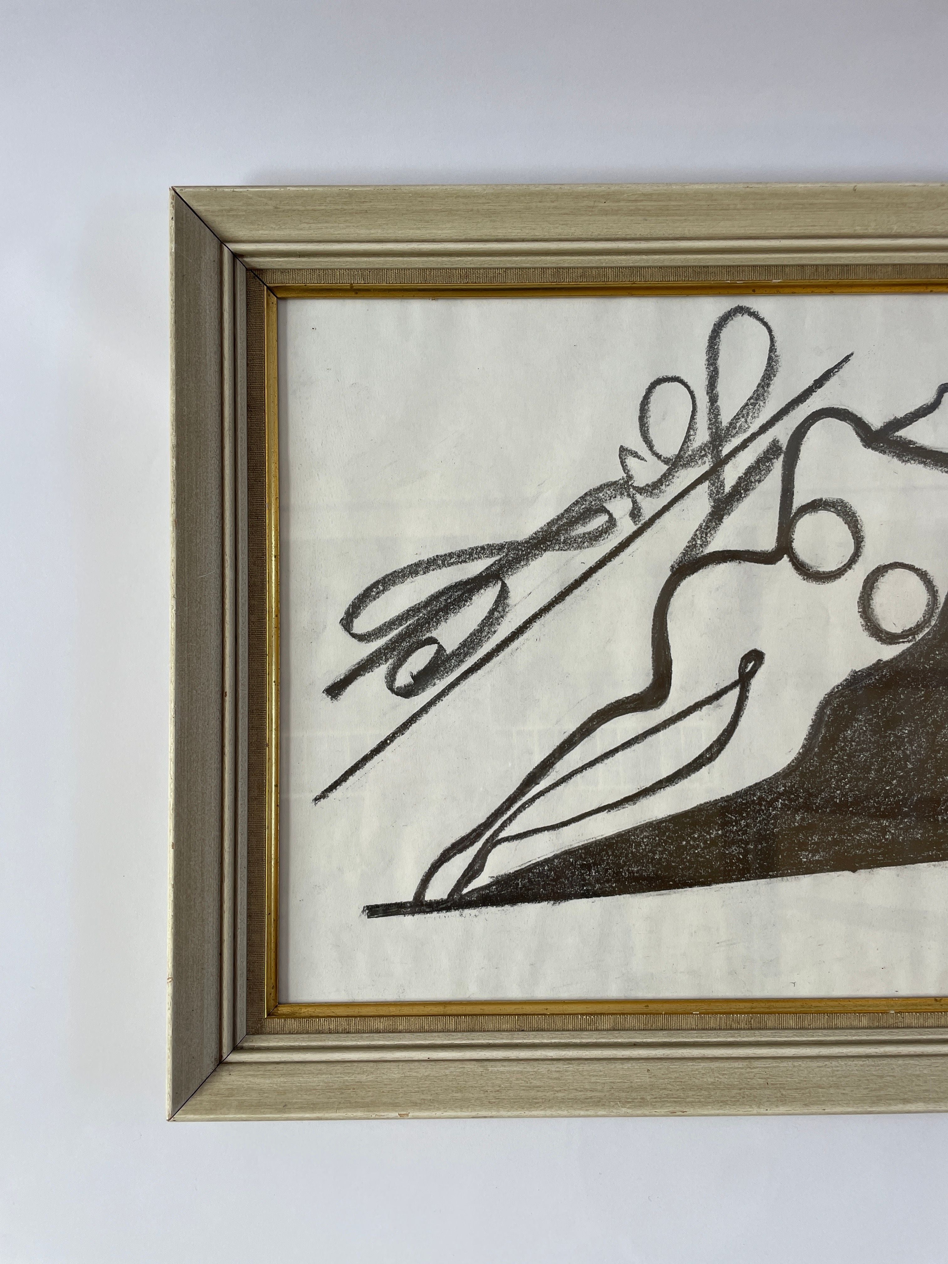 Framed "Nude" artwork by LA artist Akop Tashchyan, presented by Maud Vaughan, showcases bold black curves and lines on a partially visible white background. It is encased in a simple wooden frame with a light finish.