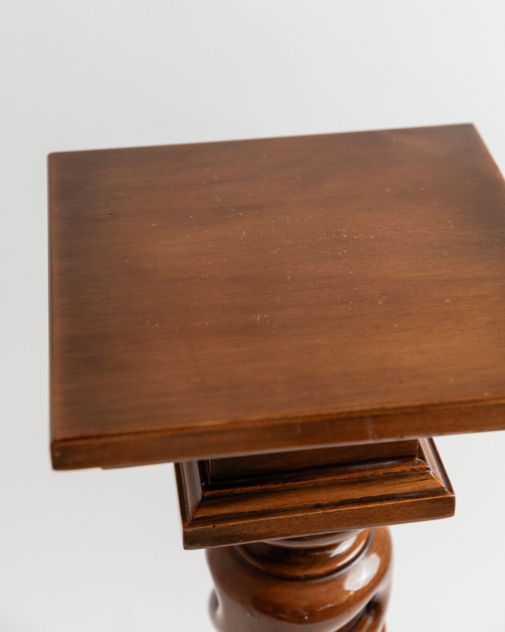 The Bottega Jacobs' Wooden Stand from Italy, 1960s, features a polished brown finish. Handcrafted with solid wood, it has a slightly reflective tabletop resting on a carved pedestal base, showcased elegantly against a plain white background.