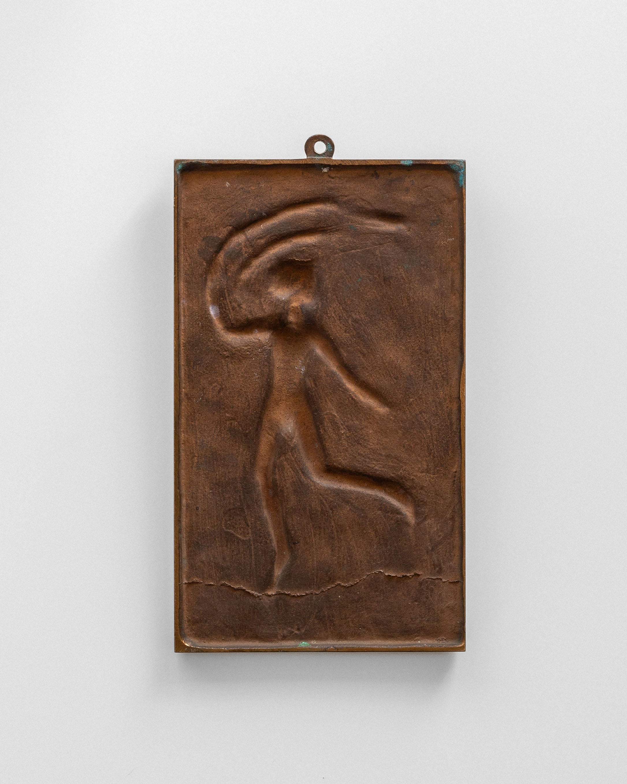 The Bronze Wall Relief by David Jahrl from Spigel features a rectangular bronze design showcasing Swedish Grace with an abstract dancing figure. It's set against a light gray background with dynamic curved lines above the head.