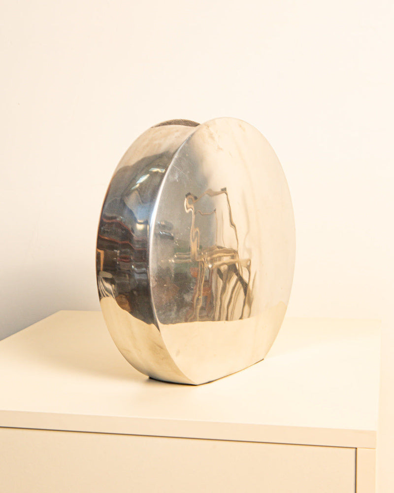 Italian circular cast-aluminum vase showing reflective surface detail