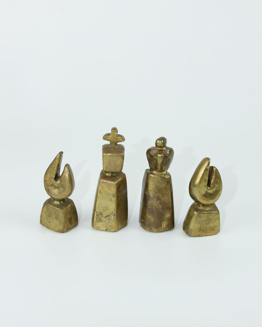Four brass chess pieces detail showing king queen and pawns from brutalist set