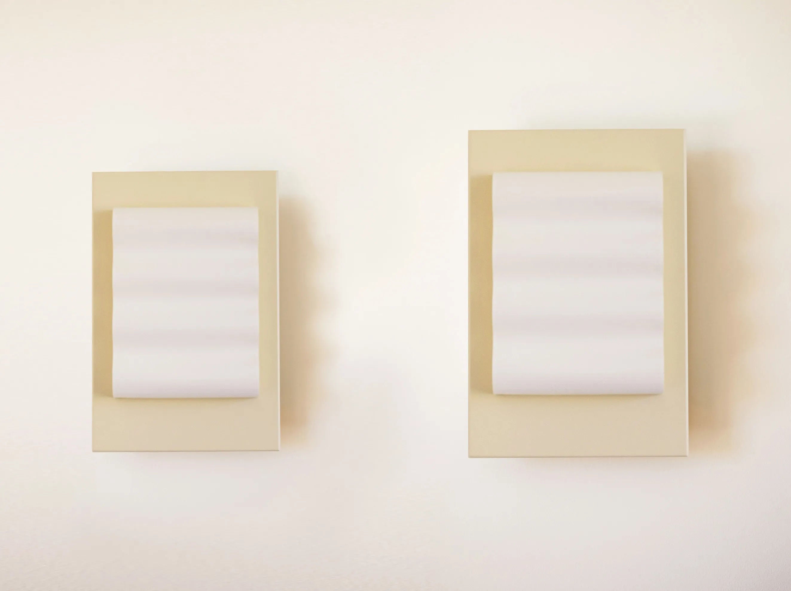 Two handcrafted Wall Light Frame OW S sconces by Violaine d'Harcourt, featuring cream bases and wavy white diffusers, are mounted on a light wall, enhancing the clean and modern minimalist aesthetic.