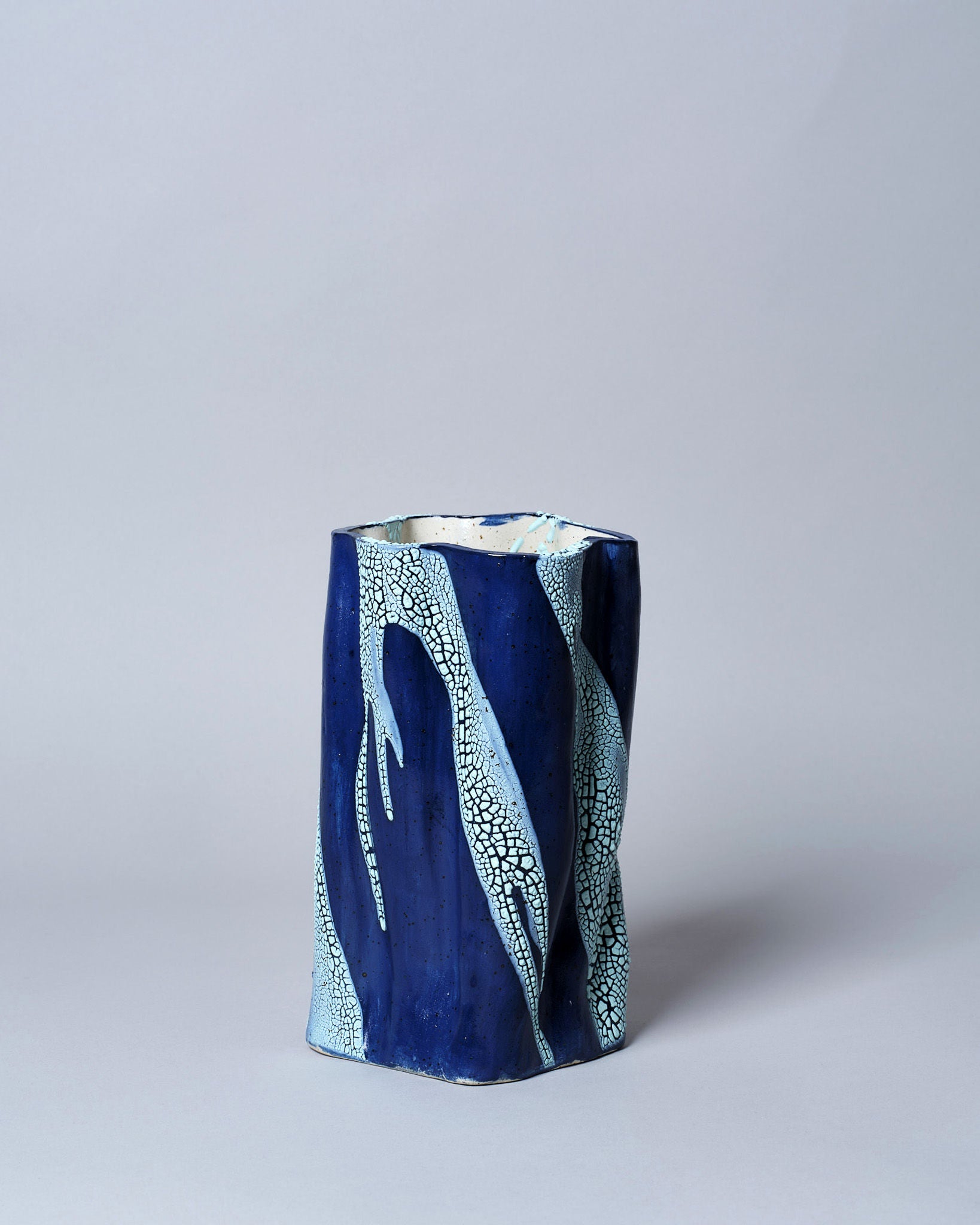 The Swirly Vase Blue and Light Blue by Astrid Öhman is a handmade blue stoneware piece, with a rectangular shape and intricate white branching patterns, set against a plain light gray background.