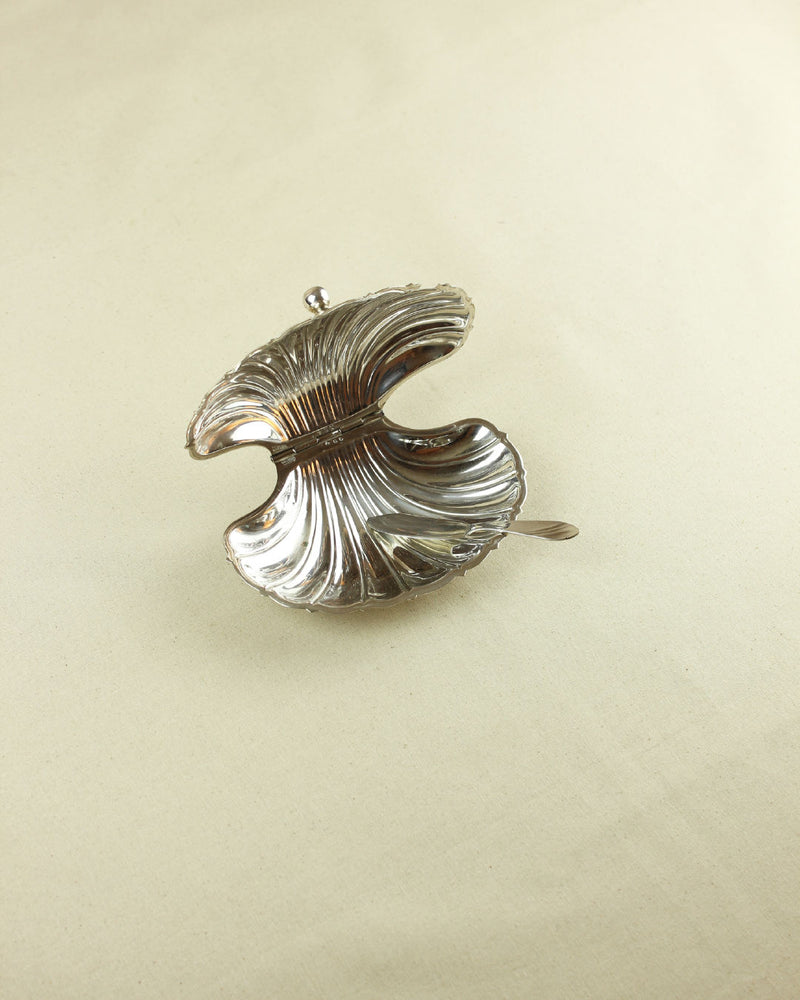 Silver shell-shaped butter dish with ribbed decorative pattern