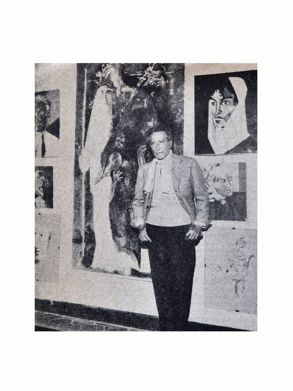A person, dressed in a vintage jacket and trousers, stands in front of a wall displaying various abstract artworks. The artworks include surreal and expressionist paintings featuring human faces and figures. The black-and-white image evokes a timeless quality, reminiscent of an old Maison Plage Livres de France: Revue Littéraire Mensuelle photograph.