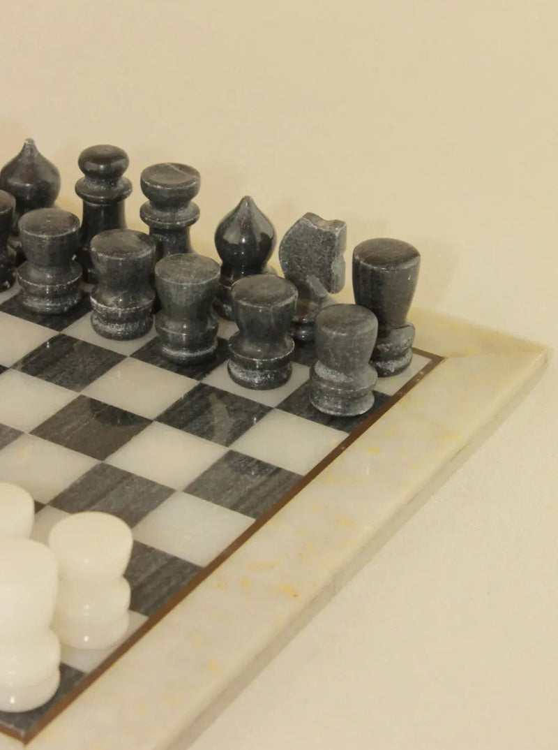 Tablero de ajedrez en mármol blanco y negro con piezas talladas a mano