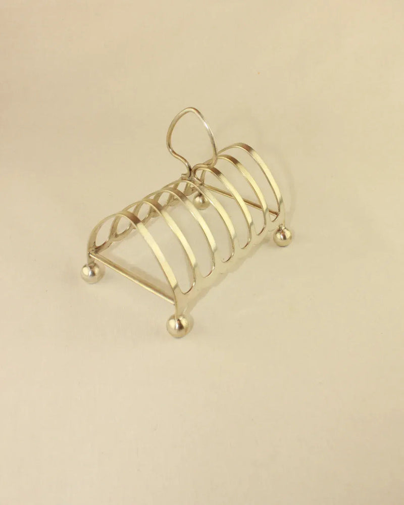 A vintage silver toast rack with six slots for holding toast slices on a breakfast table