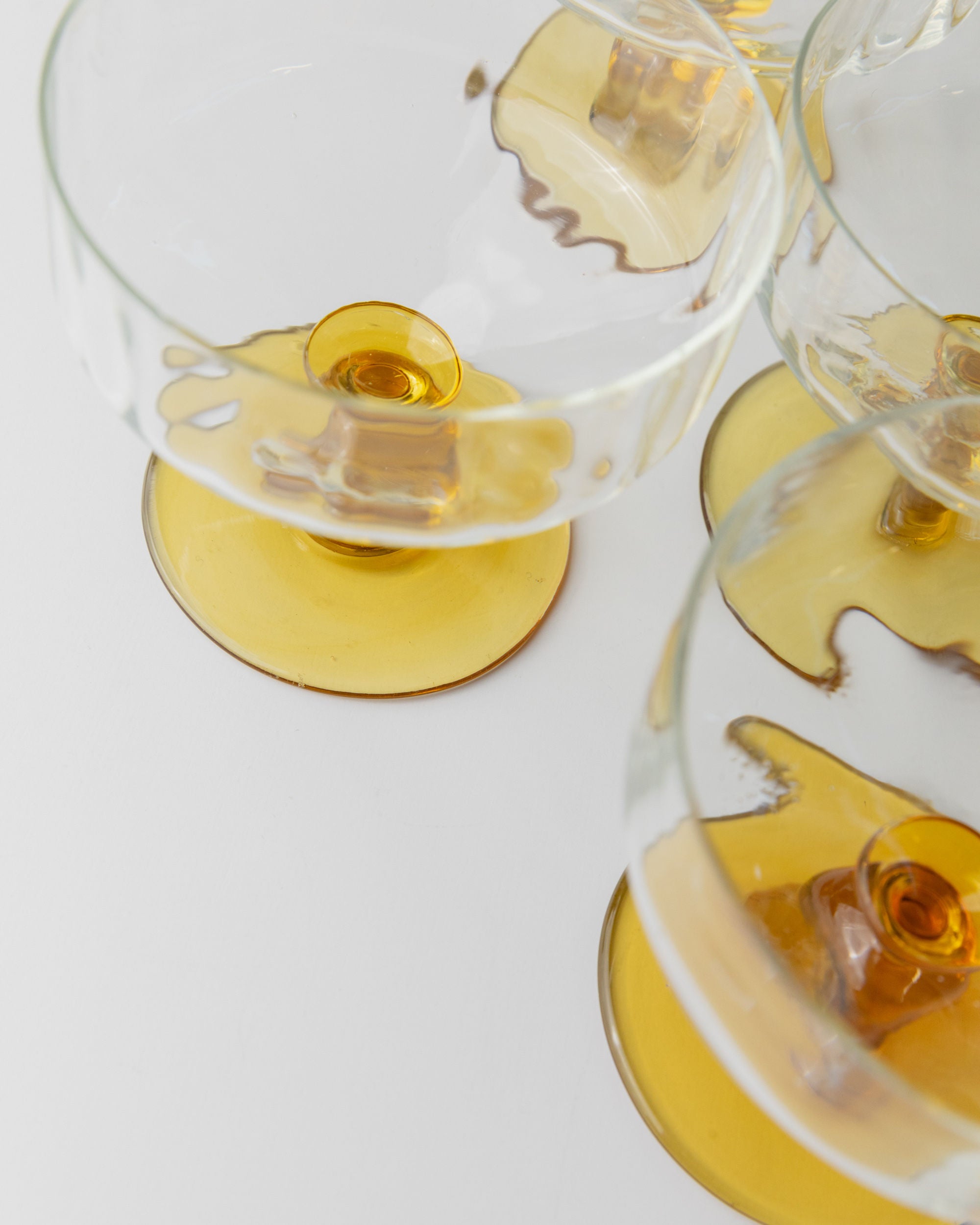 A close-up of Bottega Jacobs' Set of 6 Murano Glass vessels highlights their vintage elegance with wide, shallow bowls and short stems. The ripple texture and amber base showcase mid-century Italian design, creating beautiful overlaps on a pristine white background.