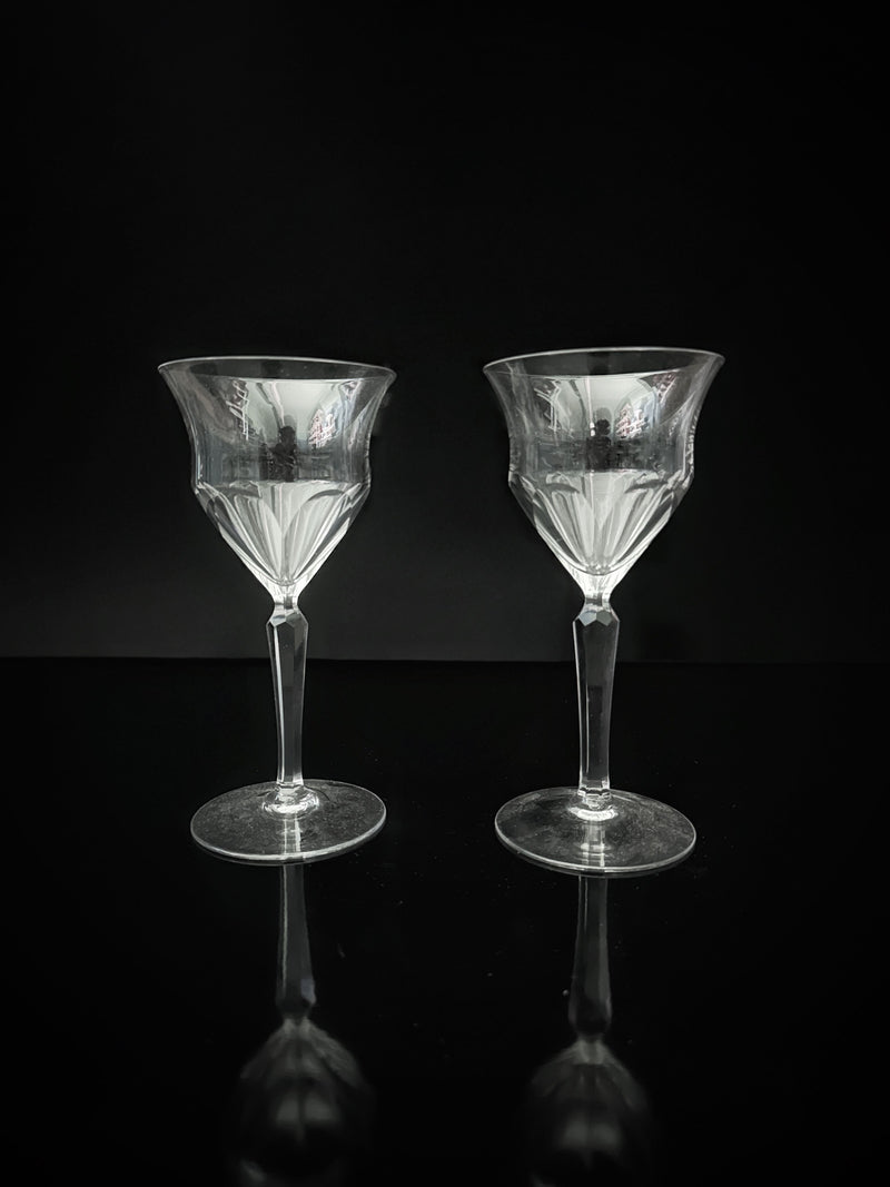 Two stunning Dodo Vintage hand-cut crystal wine glasses from the 1960s are elegantly displayed on a reflective black surface, set against a dark background.