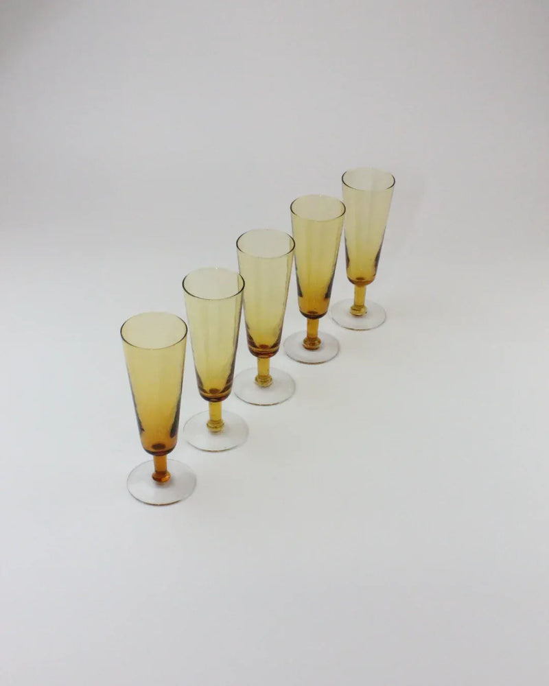Set of five amber crystal champagne flutes arranged in diagonal line