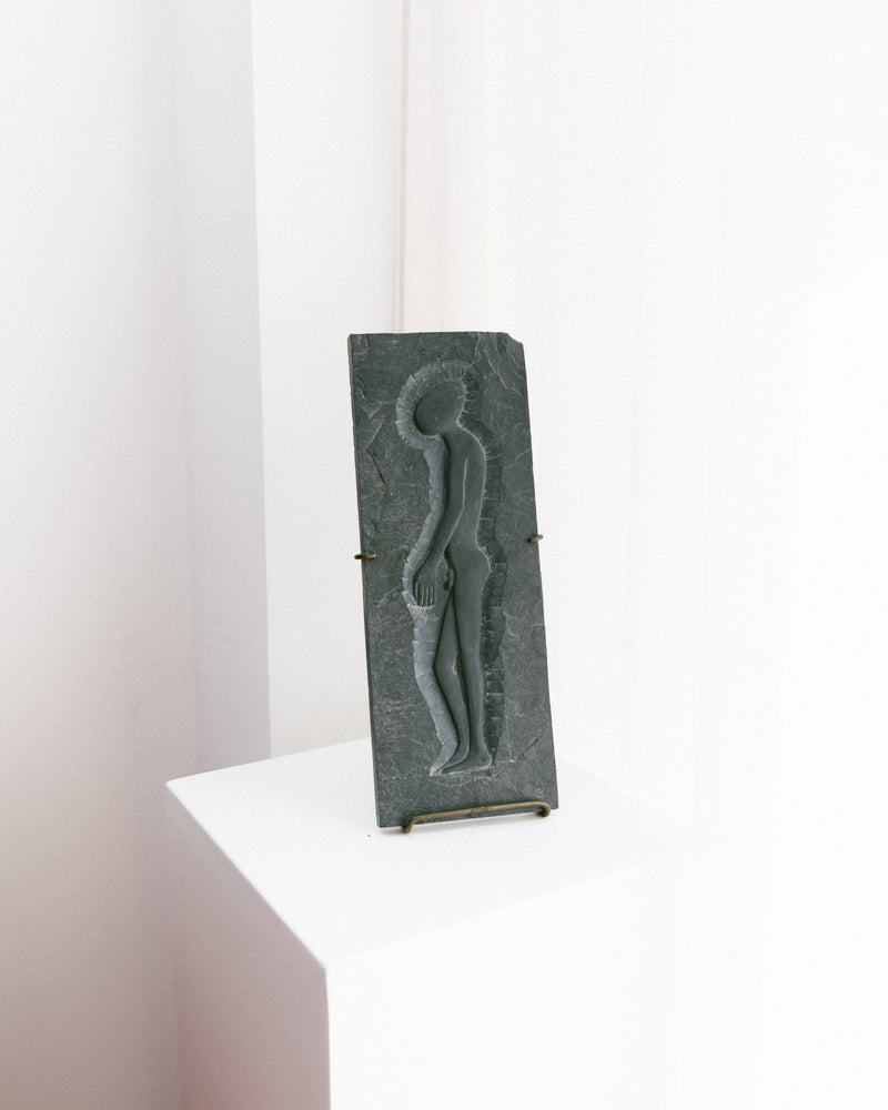 The Bottega Jacobs Slate Art Panel - Alien Man 1970 showcases a stylized human figure with relief design and textured surface, displayed vertically on a white pedestal against a minimalist background.