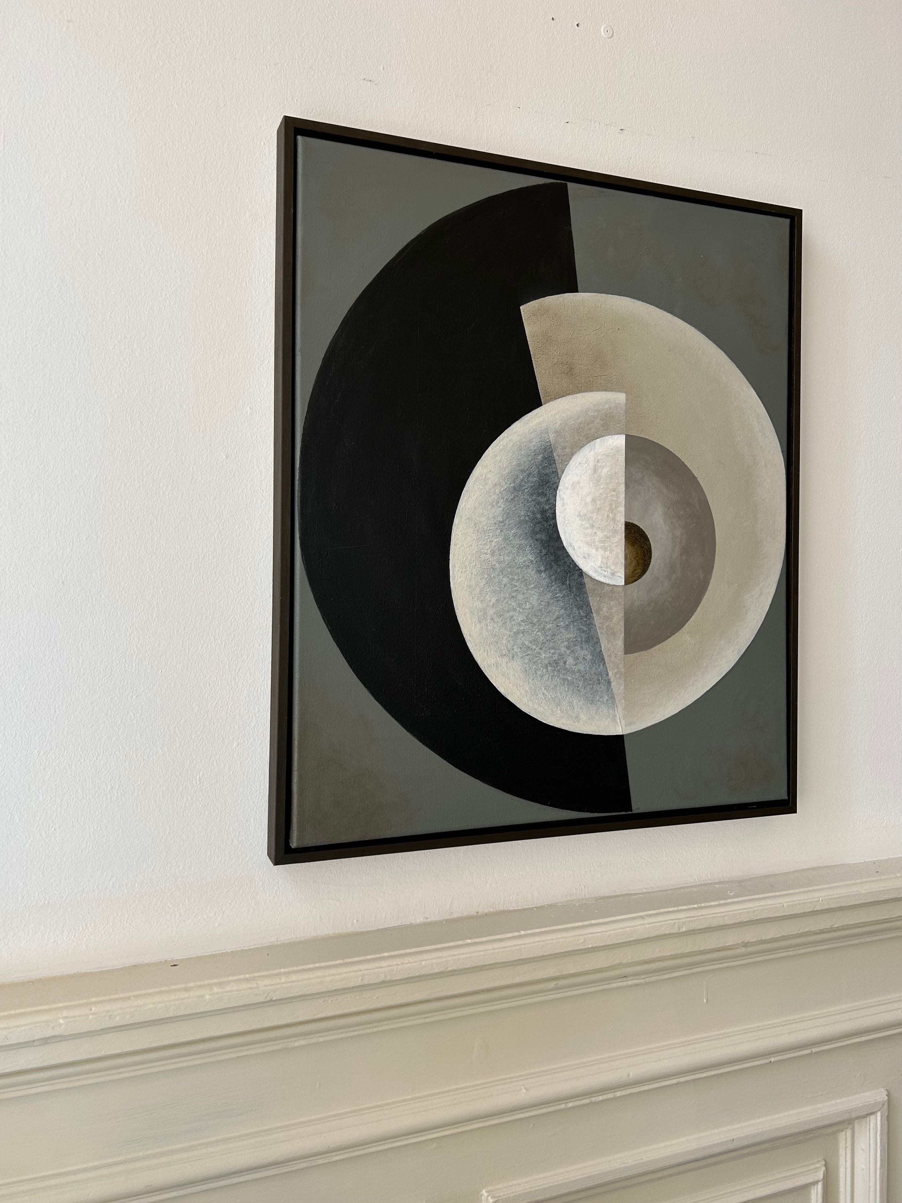 A framed "Spiralling" Painting, 2024 by Iris Bavelaar hangs on a white wall. The artwork, acrylic on canvas, features overlapping geometric shapes in shades of black, gray, and white, with a small circle in the center. Its brown wooden box frame adds warmth to the composition, enhancing the sense of depth and contrast.