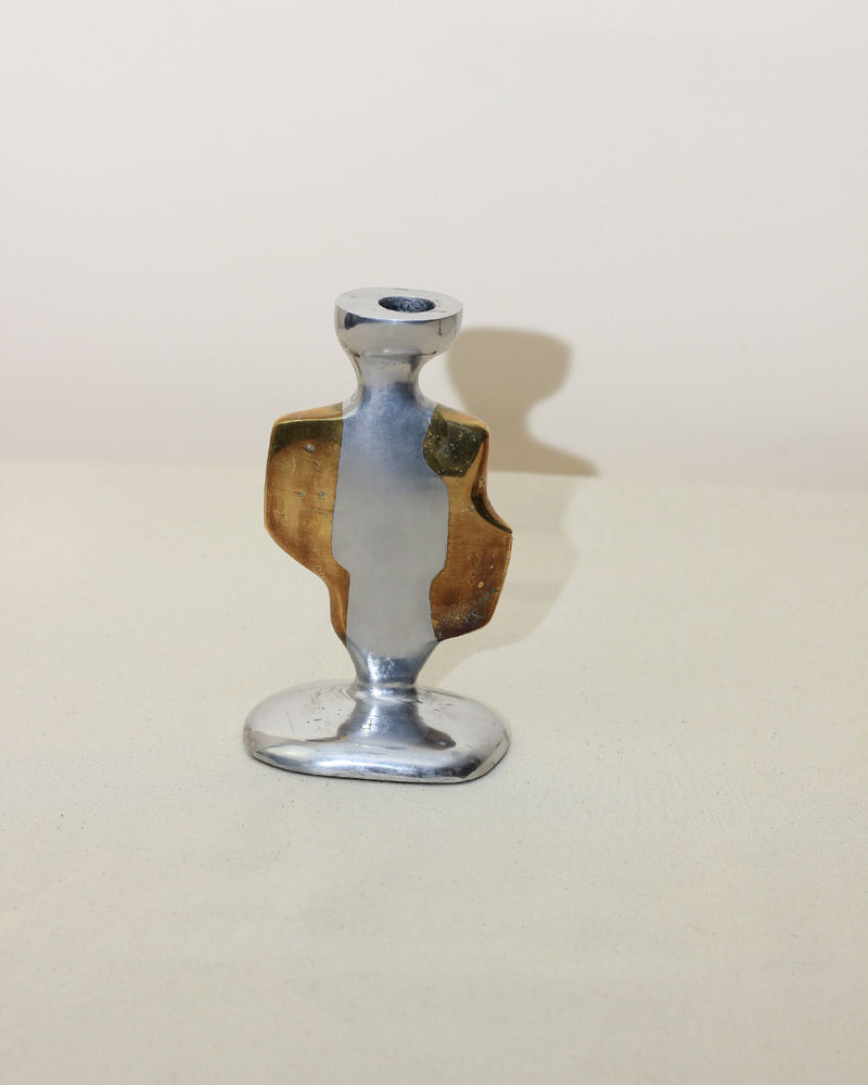 The Pair of Brutalist Candleholders by Boga Avante Shop features a modern, abstract design in aluminum and brass with silver and gold tones, smooth curved lines, and an asymmetrical shape reminiscent of vintage brutalist pieces.