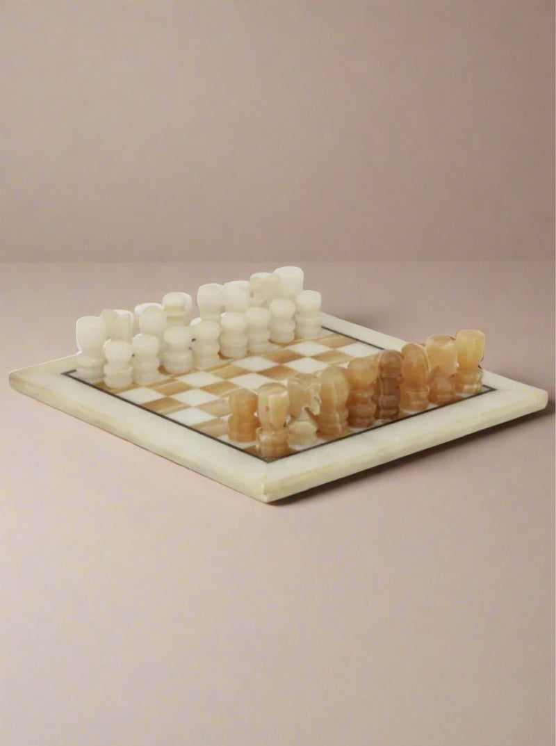 A vintage chessboard, the Vintage Marble Chessboard by Boga Avante Shop, features a marble stone board with alternating square patterns and hand-carved pieces made from marble. The pieces are in two colors, with creamy white pieces on one side and light brown pieces on the other, all arranged for the start of the game.