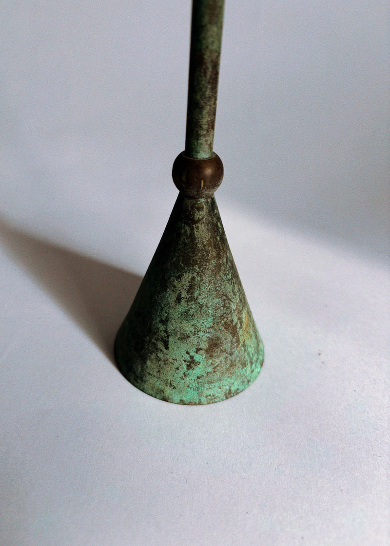 A close-up of the base and lower stem of a Huerto Set of 3 Postmodern 80's Candle Holders highlights their vintage green patina and conical metal form against a plain white background.
