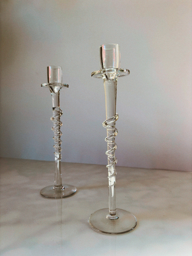Huerto Clear Glass Candleholders stand tall on a glossy surface, each handblown piece featuring a spiral design around the stem against a softly lit, neutral background.