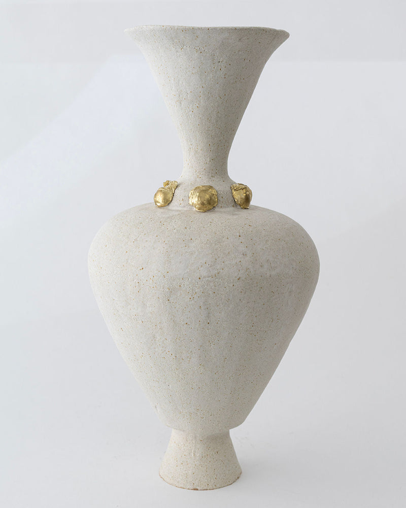 The Isolated n.24 Vase by Canoa Lab is a tall, light beige ceramic piece with a wide flared mouth, narrow neck, and four small gold accents at the base of the neck. Mediterranean-inspired design shown against a plain white background.