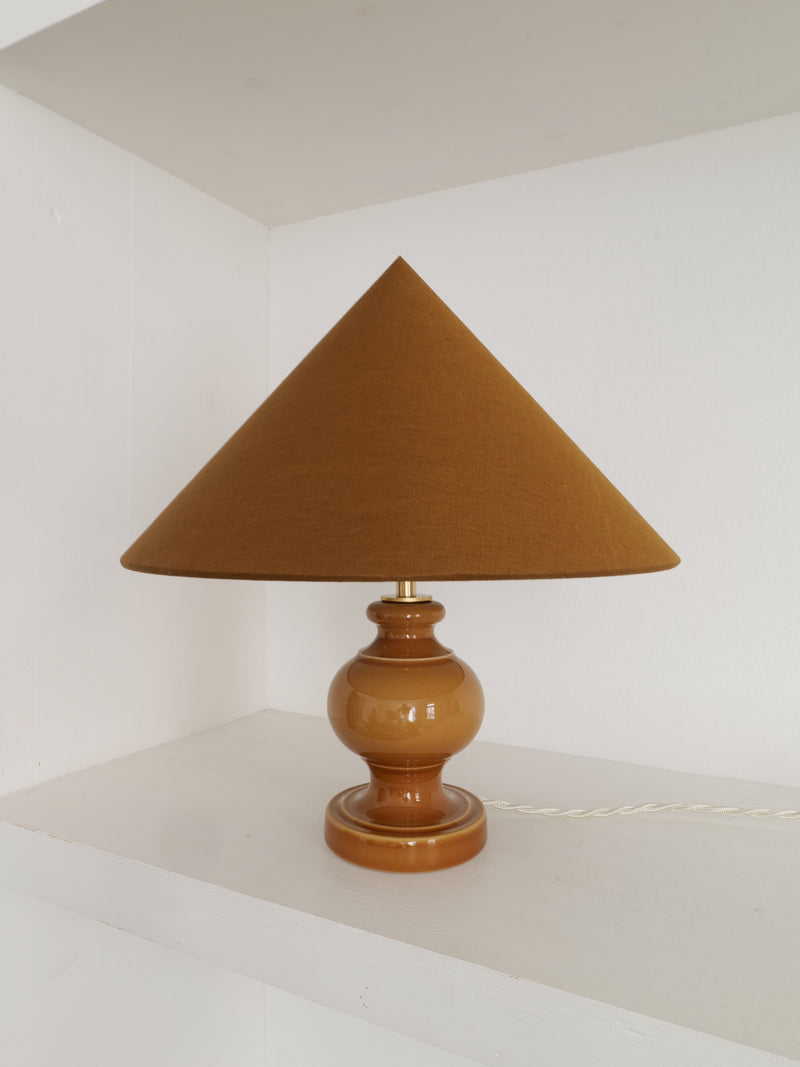 Brown ceramic table lamp with conical fabric shade and curved base