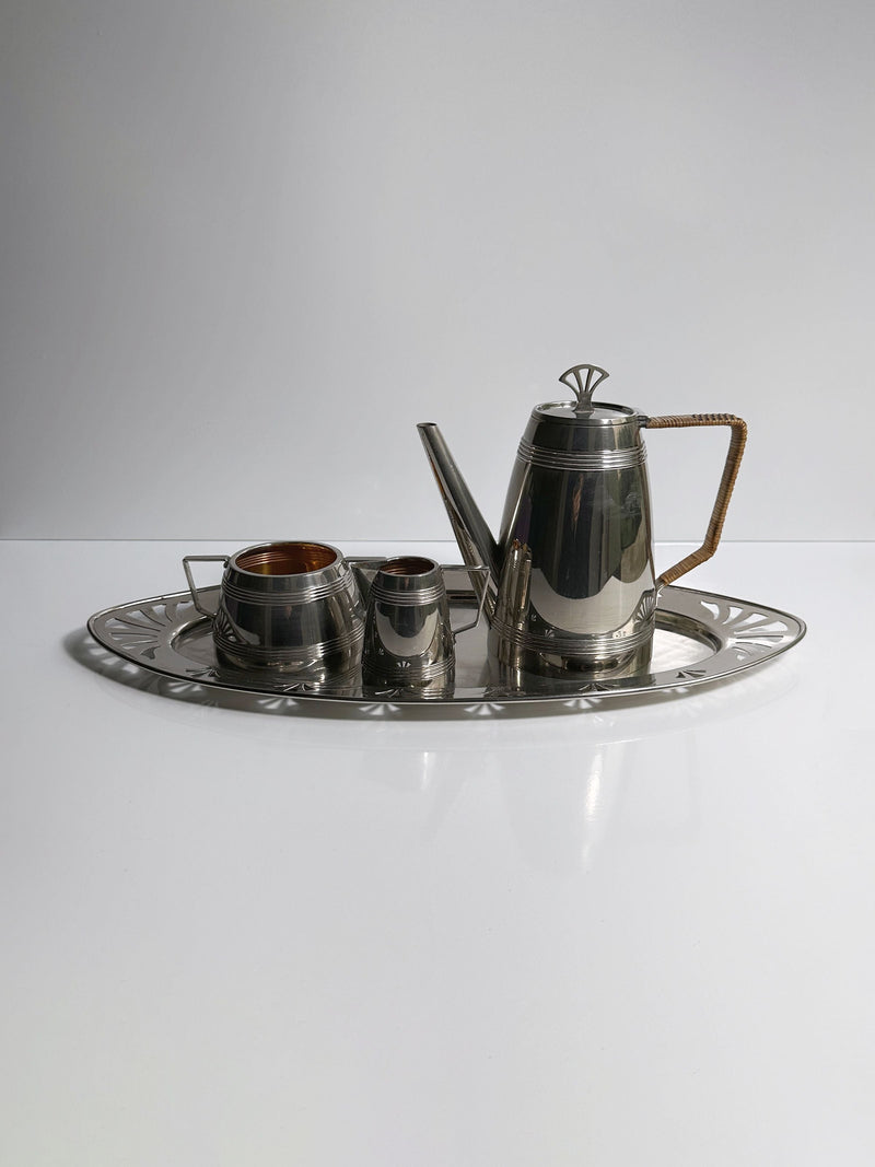 The 1930s Art Deco Silver Coffee Set by Dodo Vintage includes a teapot, sugar bowl, creamer, and tray with geometric designs and angled handles, embodying sleek French Art Deco style against a plain white background.