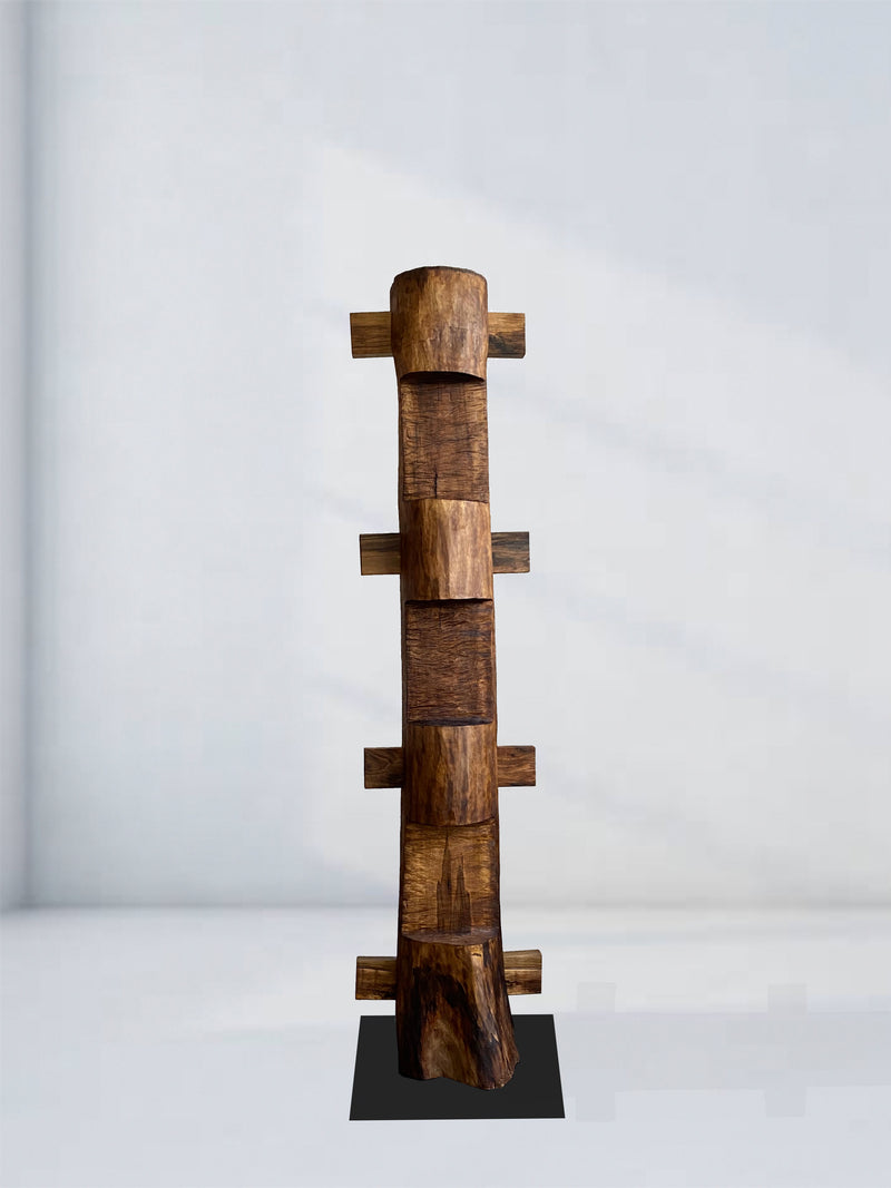 The 'Die Nacht' Sculpture by Eloi Schultz is a tall, vertical walnut totem with staggered rectangular blocks and mortise and tenon joints, standing on a black base against a plain background. Each piece is made to order.