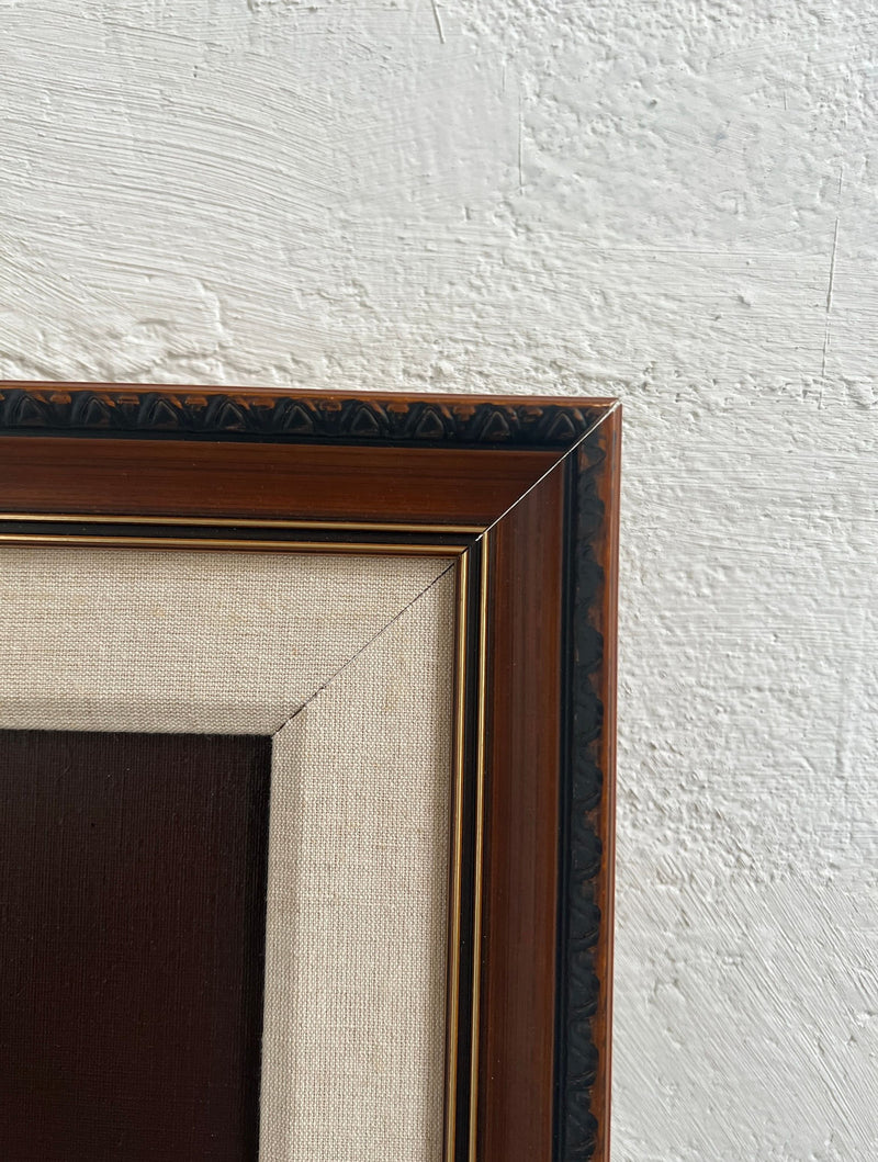 A close-up of the top right corner of Veter Vintage’s “Still Life Painting by Jan Palmu, Finland 1986,” featuring a brown wooden frame with black and gold details, beige canvas border, and textured white wall background.