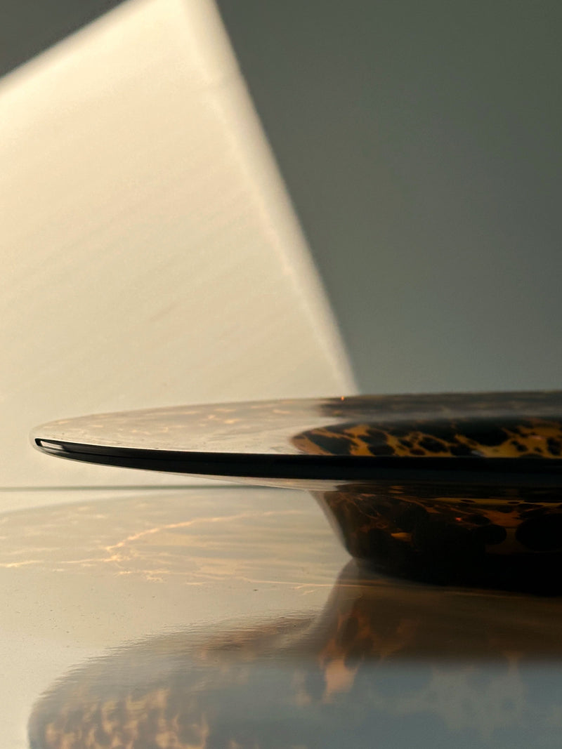 Profile view of Murano tortoise glass fruit bowl with reflection