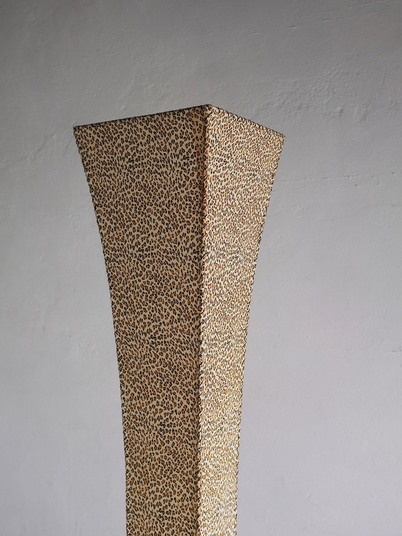 The Veter Vintage Leopard Print Floor Lamp (1980s) is a tall, narrow, four-sided lamp with a flared top and beige-brown leopard pattern, set against a plain light gray wall.