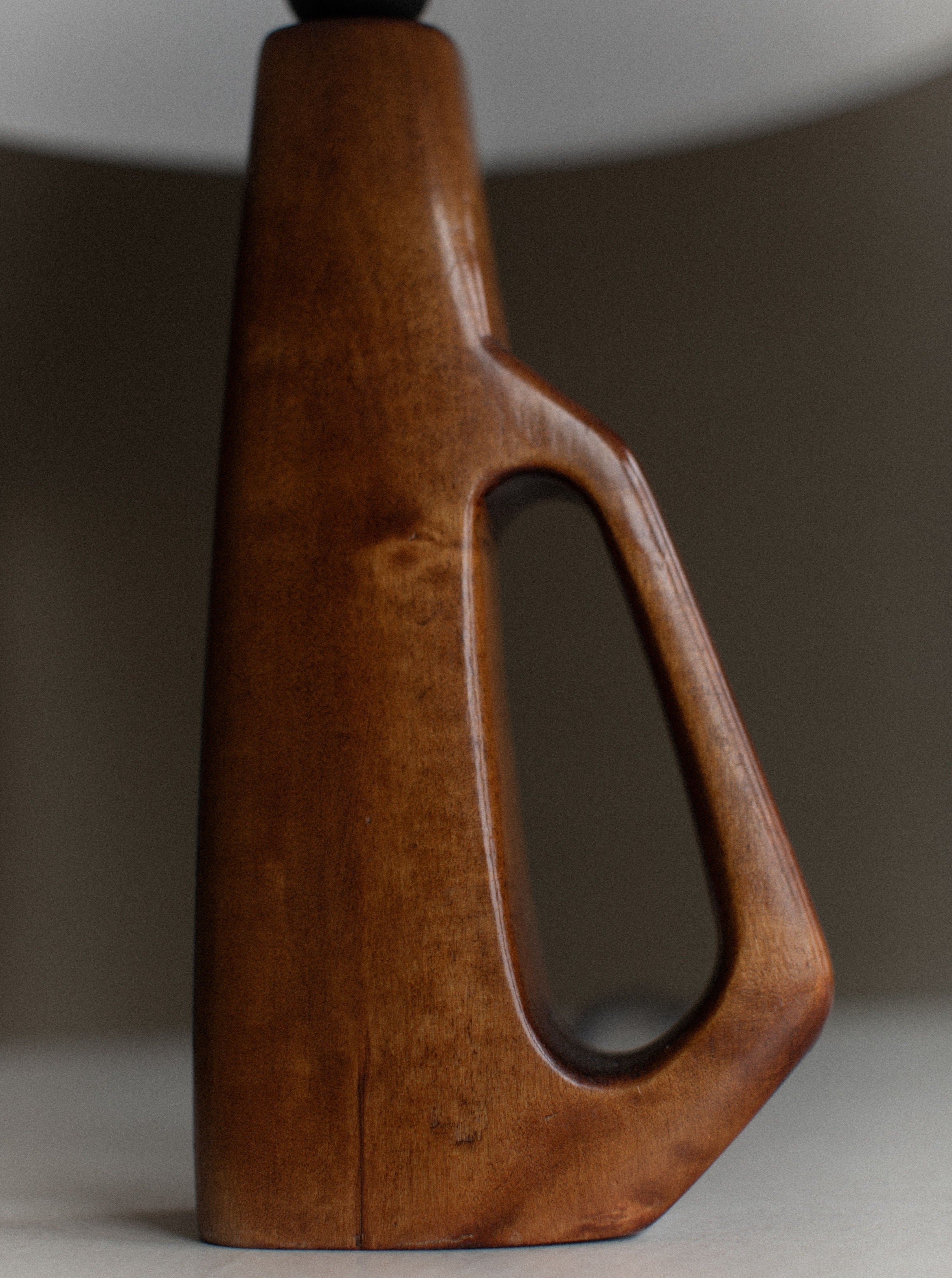 A close-up of the 1960's Wooden Lamp by Out For Lunch showcases its hand-carved details. The rich brown finish highlights the natural grain. This sleek, modern design emphasizes craftsmanship and elegant simplicity, drawing inspiration from mid-century design.