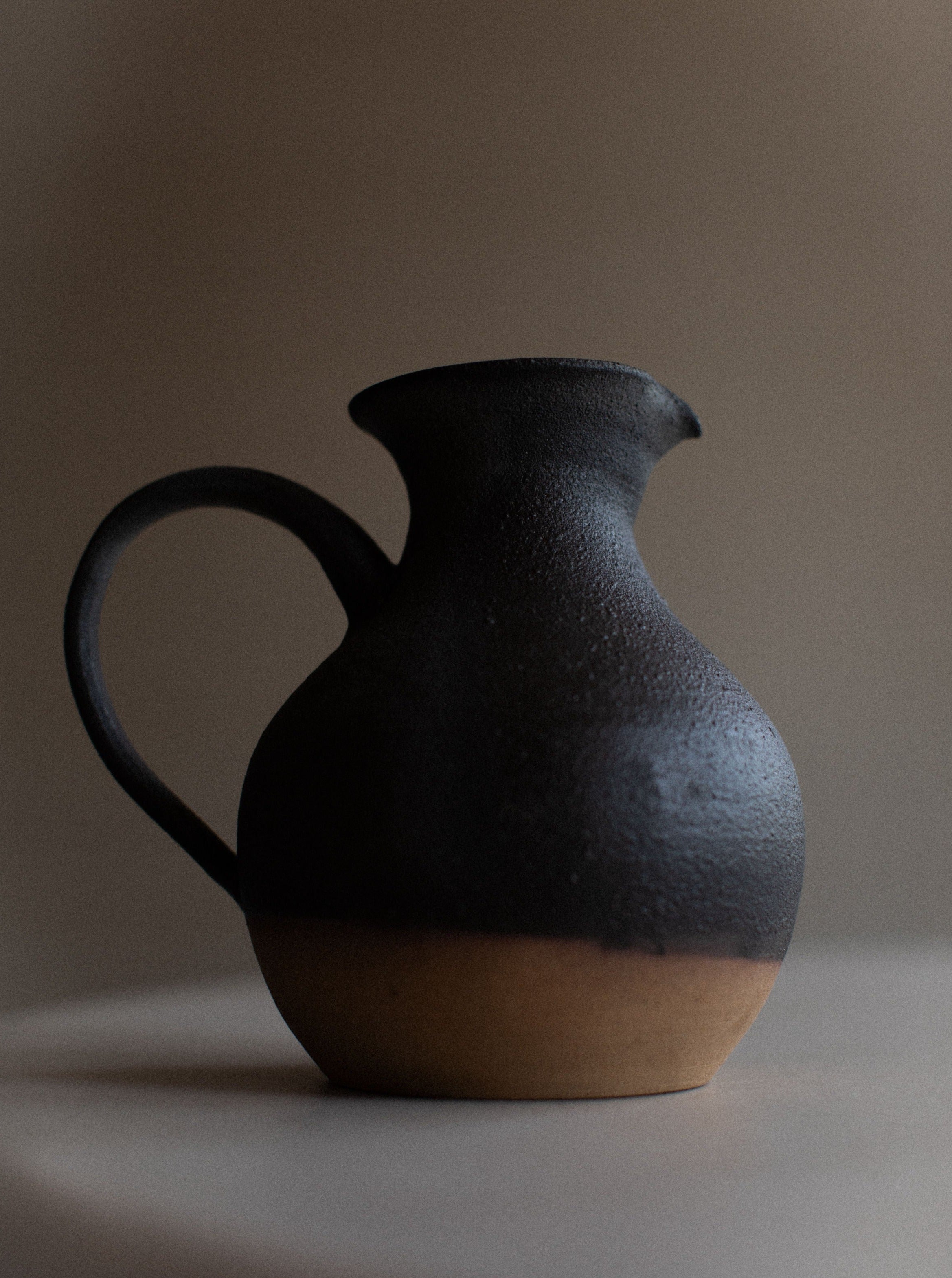 Handcrafted stoneware pitcher with a textured, rustic design and a large handle