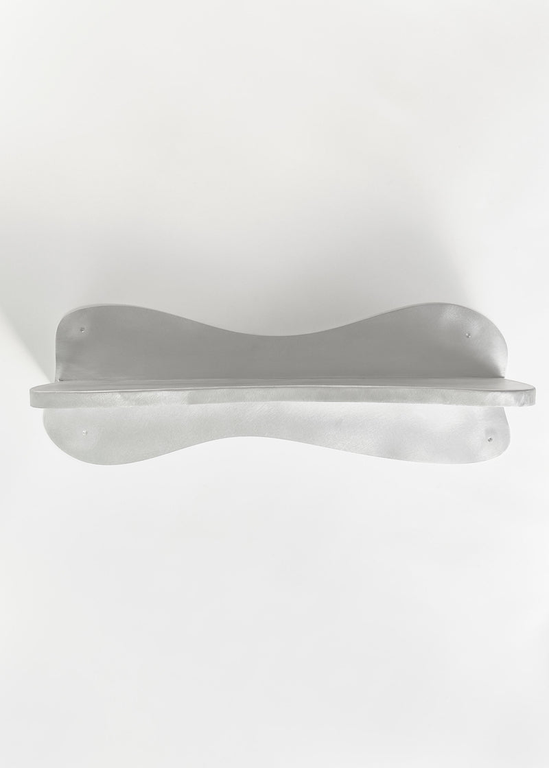 The Big Shelf by Six Dots Design is a white, curved object with smooth lines and a symmetrical shape, mounted against a white background, resembling an abstract sculpture and offering a contemporary artistic appearance.
